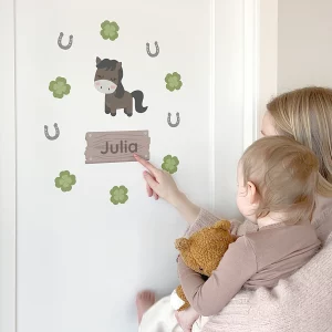 Dørdekor for barnerom med hestemotiv og personlig navneskilt på en dør, der en kvinne viser barnet designet.