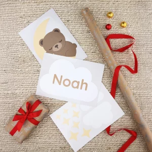Klistremerker til dør på ark med en bjørn som sover på en måne og en sky hvor det står "Noah" omgitt av innpakningspapir til jul.