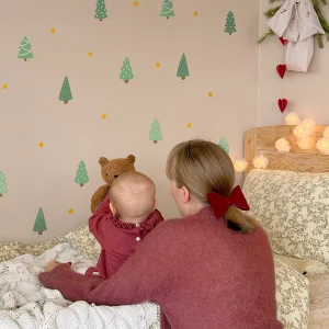 Barn som sitter på seng og peker på veggdekor med jule- og naturmotiver.