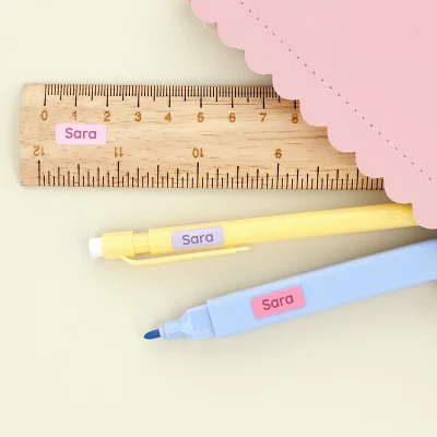 linjal, blyant og penn i rosa pennal med minilapper i rosa, mørk rosa og lilla farge med gul bakgrunn