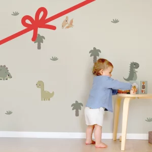 Liten gutt leker med byggeklosser ved et lite bord i et barnerom med dinosaurmotiver på veggen.