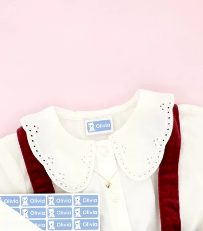 Black Week salg -20% på alt! Barnesko og barnekjole med navnelapper plassert på klærne, omgitt av snøfnugg-dekor.