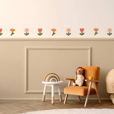 Veggdekor med blomsterdesign i myke farger på veggen over en koselig stol i et barnerom.