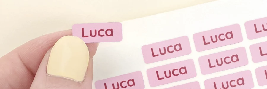 Bilde av navnelapper med navnet Luca i fargerike design, perfekte for å dekorere barneutstyr og leker. Navnelappene er synlige på papirark og en leke med skinnende overflate, noe som gjør dem ideelle for å forhindre bortglemte eller mistede ting. Perfekte for både hjemmebruk og i barnehagen.