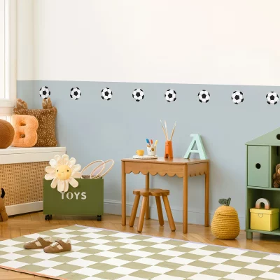 Lekent barnerom med veggdekor av fotballer, en koselig pult med fargeblyanter, og lekkert oppbevaringsmøbel for leker. Perfekt for små fotballentusiaster som ønsker et inspirerende og stilrent sted å leke og lære.
