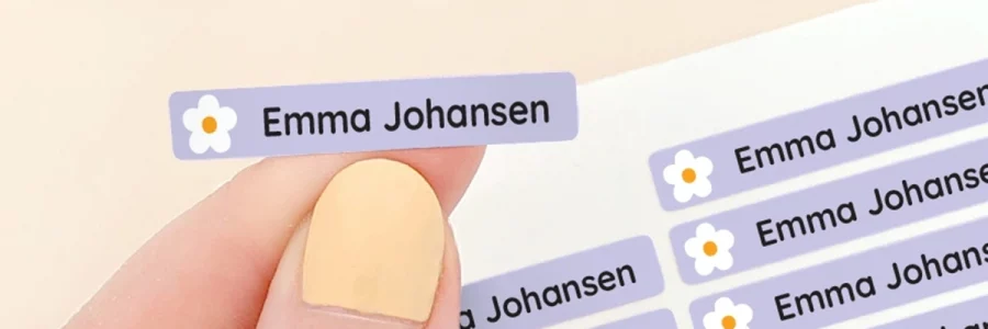 Navnelapper i lyse farger med navn Emma Johansen, designet for å brukes på barnas eiendeler. Lappene har en søt blomsterdetalj og passer perfekt for å personliggjøre skoleutstyr eller leker. Bildet viser flere lapper i ulike fargenyanser.