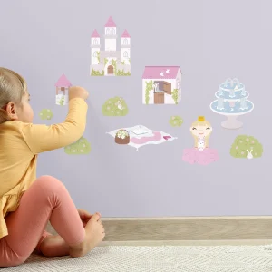 Et barn i lekse med en veggdekorasjon som viser et slott, en prinsesse, hus og selskapsdyr. Dekorasjonen skaper et fantasifullt barnerom og stimulerer kreativ lek.